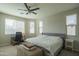 Neutral Primary bedroom with ceiling fan, bed, desk, and two windows at 18187 W Via Montoya Dr, Surprise, AZ 85387