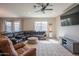 Spacious living room featuring a plush leather sectional sofa, large windows, and modern ceiling fan at 18187 W Via Montoya Dr, Surprise, AZ 85387