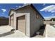 Side view of detached garage with two doors and textured siding, under a partly cloudy sky at 18542 W Luke Ave, Litchfield Park, AZ 85340