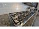 Close up view of the gas range cooktop with granite countertops and white subway tile backsplash at 18542 W Luke Ave, Litchfield Park, AZ 85340