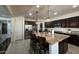 Open kitchen with a large central island, stainless steel appliances, granite countertops, and dark wood cabinets at 18542 W Luke Ave, Litchfield Park, AZ 85340