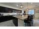The spacious kitchen features dark cabinets, a granite island with bar seating, and a subway tile backsplash at 18542 W Luke Ave, Litchfield Park, AZ 85340