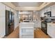 Open-concept kitchen with an island, white cabinets, stainless steel appliances, and wood floors at 18886 N 77Th Ave, Glendale, AZ 85308