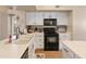 Well-lit kitchen with white cabinets, black appliances, and laminate flooring at 18886 N 77Th Ave, Glendale, AZ 85308