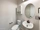 Cozy powder room featuring a pedestal sink, round mirror and a tiled floor at 2526 E Novak Way, Phoenix, AZ 85042