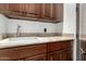 This laundry area features upper and lower wood cabinets and a white sink at 27708 N 110Th Pl, Scottsdale, AZ 85262