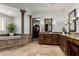 Well-appointed main bathroom with a soaking tub, tiled floor, stone columns, and a dark wood vanity at 27708 N 110Th Pl, Scottsdale, AZ 85262