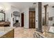 Open main bathroom features a large storage cabinet, soaking tub, vanity with marble countertop, and decorative stone column at 27708 N 110Th Pl, Scottsdale, AZ 85262