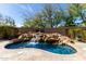 Backyard pool with rock waterfall feature and well manicured landscaping at 27708 N 110Th Pl, Scottsdale, AZ 85262