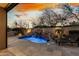 Backyard pool and patio with rock waterfall feature, mature trees, lounge seating, and a built-in bar area at 27708 N 110Th Pl, Scottsdale, AZ 85262
