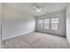 Spacious carpeted bedroom with white walls, ceiling fan, and multiple windows at 32366 N 133Rd Ln, Peoria, AZ 85383