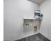 Laundry room with gray floors, storage shelf, and decorative wall art at 32366 N 133Rd Ln, Peoria, AZ 85383