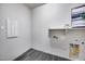 Bright laundry room features tile flooring, utility connections, and shelving for storage at 32366 N 133Rd Ln, Peoria, AZ 85383