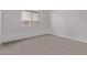 A bright bedroom features plush carpet, a large window, and neutral walls at 40499 W Michaels Dr, Maricopa, AZ 85138