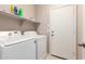 Functional laundry room with a modern washer, dryer, and shelving for storage of detergents and supplies at 42266 W Sparks Dr, Maricopa, AZ 85138