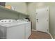 Laundry room with white washer and dryer, overhead shelving, and a tiled floor at 4914 E Palm Beach Dr, Chandler, AZ 85249