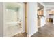 Hallway view of a full bathroom and kitchen with white tile and natural wood cabinets at 5303 N 7Th St # 109, Phoenix, AZ 85014