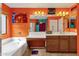 Bright bathroom with orange walls featuring a bathtub, vanity, and large mirror at 5415 E Mckellips Rd # 24, Mesa, AZ 85215