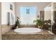 Bright bathroom featuring a soaking tub with tile surround, stained glass window, and fresh plants at 5810 E Calle Marita E --, Cave Creek, AZ 85331