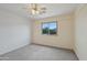 Neutrally decorated bedroom features a ceiling fan, plush carpeting, and a bright sunny window at 11263 S Oakwood Dr, Goodyear, AZ 85338