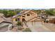 View of front exterior featuring a three car garage, desert landscaping, and a light colored stucco at 11263 S Oakwood Dr, Goodyear, AZ 85338