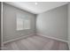 A bedroom featuring neutral carpet, light gray walls, white trim, and a large window at 11522 W Deanne Dr, Youngtown, AZ 85363