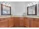 Dual-sink bathroom with granite countertops, wood cabinetry, and framed mirrors at 1225 E Sea Gull Dr, Gilbert, AZ 85234