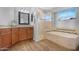 Bathroom with a corner tub, walk-in shower, and a wood-stained vanity with granite countertops at 1225 E Sea Gull Dr, Gilbert, AZ 85234