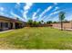 Spacious backyard with a well-maintained lawn, mature trees, and a covered patio area at 13516 W Windsor Blvd, Litchfield Park, AZ 85340