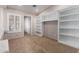 A carpeted room with built-in shelves and a bright window with white plantation shutters at 13516 W Windsor Blvd, Litchfield Park, AZ 85340