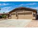 Spacious three-car garage with stone veneer accents and a wide driveway with desert landscaping at 13516 W Windsor Blvd, Litchfield Park, AZ 85340