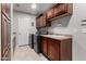 Well-organized laundry room with modern washer and dryer, wooden cabinets, and a utility sink at 13516 W Windsor Blvd, Litchfield Park, AZ 85340