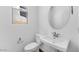 Well-lit powder room features a pedestal sink, oval mirror, and standard toilet at 14636 W Sand Hills Rd, Surprise, AZ 85387