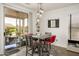 A modern dining area features a gray table and red upholstered chairs, with sliding glass doors leading to an outdoor patio at 15900 W Autumn Cir, Surprise, AZ 85374