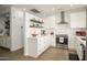 A bright kitchen with subway tile backsplash, stainless steel appliances, floating shelves, and white cabinets at 15900 W Autumn Cir, Surprise, AZ 85374