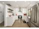Bright kitchen featuring stainless steel appliances, subway tile backsplash, white cabinets, and floating shelves at 15900 W Autumn Cir, Surprise, AZ 85374