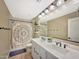 Bright bathroom with a large mirror, dual sink vanity, and shower with curtain at 18902 W Clinton St, Surprise, AZ 85388