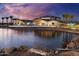 Stunning exterior of the community clubhouse reflecting in a pond with a fountain at dusk at 25069 N 174Th Ln, Surprise, AZ 85387
