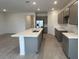 The kitchen features a quartz island, gray cabinets, stainless steel refrigerator, and stylish tiled flooring at 25170 W Wayland Dr, Buckeye, AZ 85326