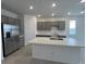 Stylish kitchen with a quartz island, stainless steel refrigerator, gray cabinets, and tiled flooring at 25170 W Wayland Dr, Buckeye, AZ 85326