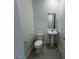Cozy powder room features pedestal sink and toilet, accented by tiled flooring, providing a clean aesthetic at 25170 W Wayland Dr, Buckeye, AZ 85326