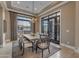 Bright dining room features modern chandelier, neutral colors, and beautiful views through large picture window and french doors at 2742 W Monterey Pl, Chandler, AZ 85224