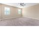 Large carpeted bedroom with two windows, a ceiling fan, and neutral-colored walls at 30303 W Whitton Ave, Buckeye, AZ 85396