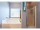 Bathroom featuring a white tiled tub and a glass-enclosed shower, illuminated by a window at 33425 N Roadrunner Ln, San Tan Valley, AZ 85144