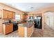 Functional kitchen features wood cabinetry, a center island, black appliances and tile flooring at 33425 N Roadrunner Ln, San Tan Valley, AZ 85144