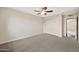 Bright bedroom with neutral walls, gray carpet, closet, and ceiling fan at 4211 W Yorkshire Dr, Glendale, AZ 85308