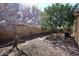 View of the stone covered backyard featuring mature trees, a brick wall fence, and a sunny atmosphere at 43857 W Bedford Dr, Maricopa, AZ 85138