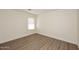 Cozy bedroom with wood flooring, a large window and white walls at 43857 W Bedford Dr, Maricopa, AZ 85138