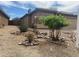 Tan single-story home featuring a tile roof, a two-car garage, and a gravel yard with shrubbery at 43857 W Bedford Dr, Maricopa, AZ 85138