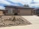 Tan single-story home featuring a tile roof, a two-car garage, and a gravel yard at 43857 W Bedford Dr, Maricopa, AZ 85138
